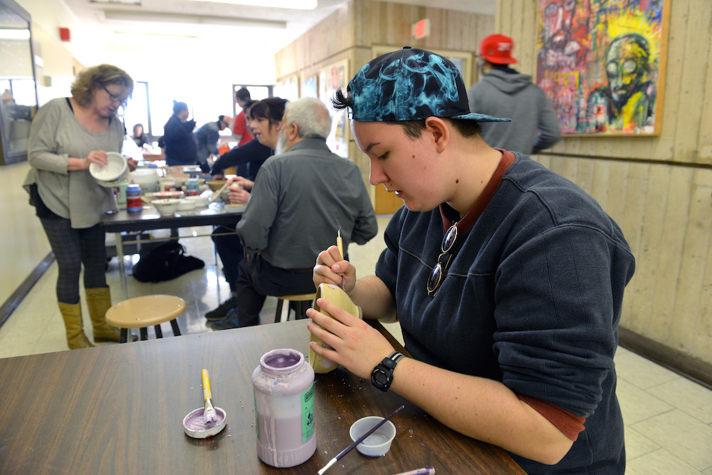 A student painting a clay bowl